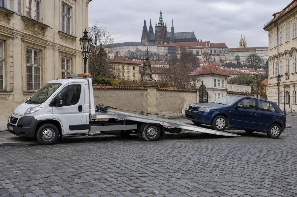 Odtahovka nakládá modrou Škodu Fabii v Loretánské ulici na Hradčanech, v pozadí Pražský hrad