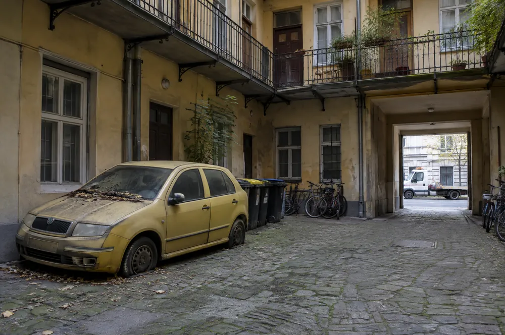 Zaprášená žlutá Škoda Fabia s prázdnými pneumatikami stojí roky ve dvoře činžovního domu na Novém Městě